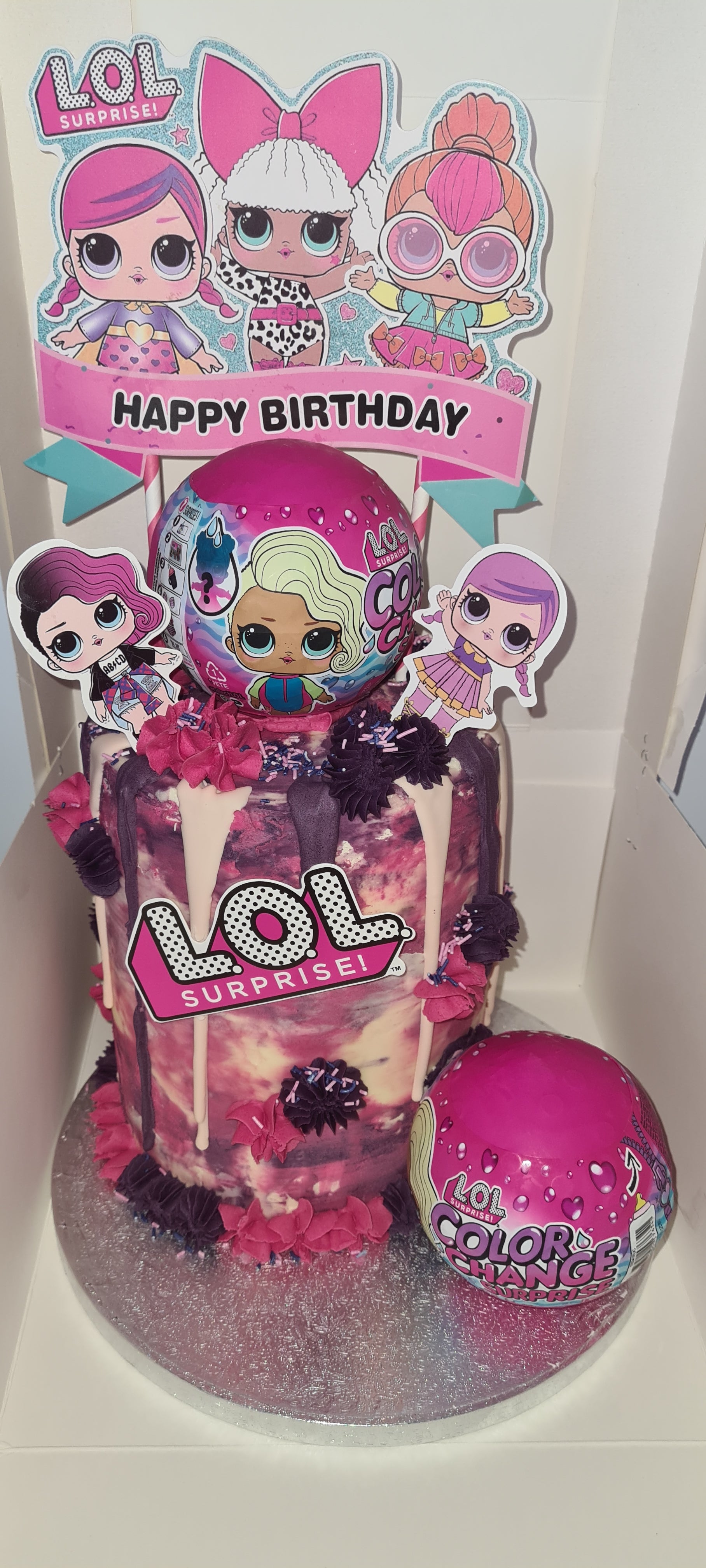 A pink happy birthday bespoke cake with a LOL surprise theme